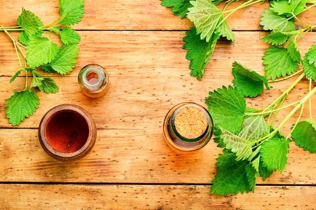 Essenza di ortica e foglie di ortica fresche. Ortiche nella medicina di erbe. Concetto di medicina alternativa