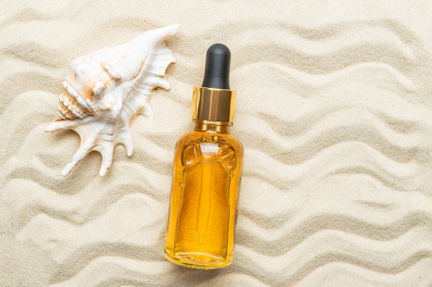 Essenza di siero di olio in bottiglia di vetro flatlay Cosmetici naturali per la cura della pelle Olio di protezione solare per proteggere viso e corpo nelle giornate estive Tema del mare con sabbia e conchiglie