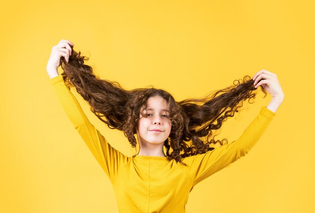 Essere di umore divertente. capelli sani e forti. buon shampoo o lozione. salone di bellezza parrucchiere. Concetto di capelli forti e sani. Capelli lunghi del bambino piccolo. scherzando. ragazza felice con i capelli lunghi e ventosi.