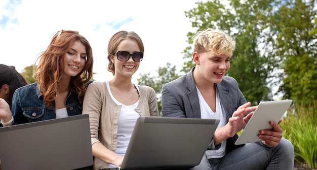 estate, comunicazione, tecnologia, istruzione e concetto adolescenziale - gruppo di studenti o adolescenti con computer portatili e tablet pc al parco o al campus