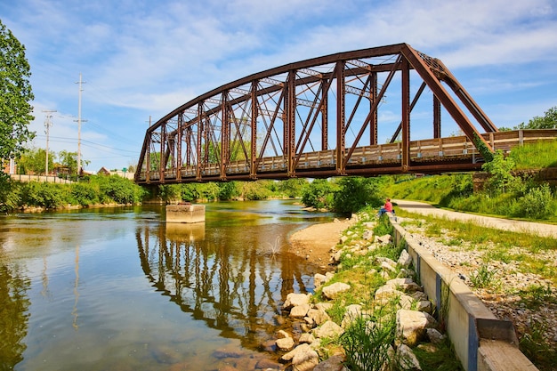 Estate con il fiume Kokosing in Ohio con una persona seduta e un vecchio ponte ferroviario pedonale