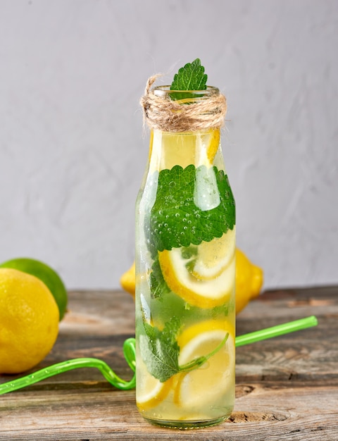 Estate limonata bevanda rinfrescante con limoni, foglie di menta, lime in una bottiglia di vetro