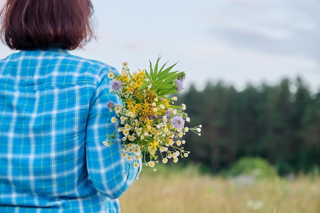 Estate natura vista posteriore della donna con mazzi di fiori di campo