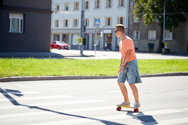 estate, traffico, sport estremo e concetto di persone - adolescente in sella a un breve skateboard da crociera moderno sulle strisce pedonali in città