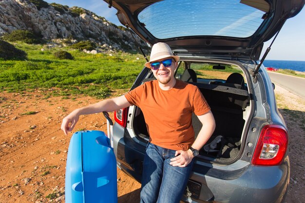 Estate, vacanza, viaggio e concetto di vacanza. Uomo vicino alla macchina pronta a viaggiare.