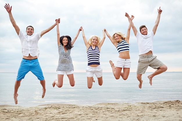 estate, vacanze, mare, turismo e concetto di persone - gruppo di amici sorridenti in occhiali da sole che camminano sulla spiaggia