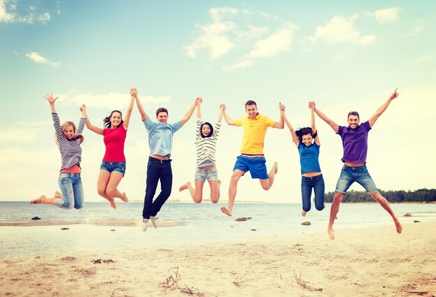 estate, vacanze, vacanze, concetto di persone felici - gruppo di amici che saltano sulla spiaggia