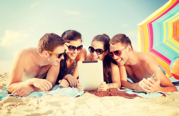 estate, vacanze, vacanze, tecnologia e concetto di persone felici - gruppo di persone sorridenti in occhiali da sole con tablet pc sulla spiaggia