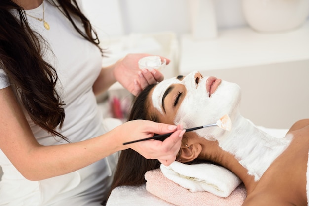 Estetica che applica una maschera sul viso di una donna bellissima