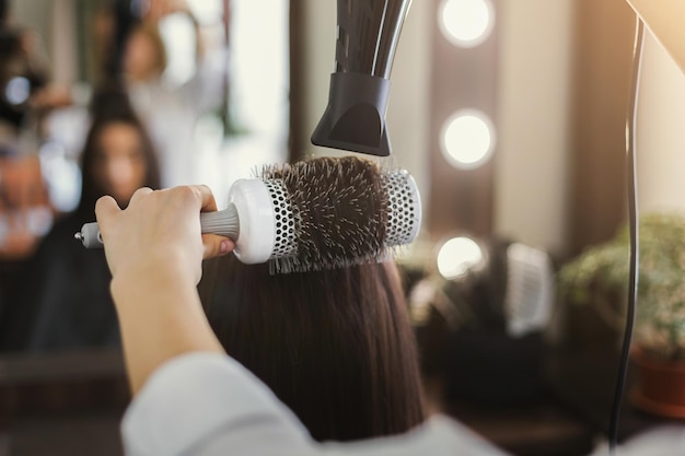 Estetista che asciuga i capelli della donna dopo aver dato un nuovo taglio di capelli al salone. Bellezza, cura, cocnept dei capelli