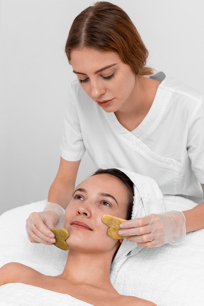 Estetista che fa routine di bellezza del viso per cliente femminile