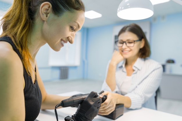 Estetista della donna nel salone dell'unghia di bellezza che fa manicure