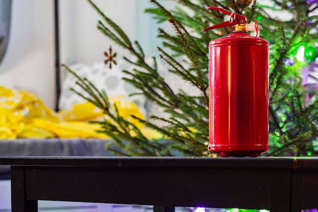 Estintore in piedi sul tavolo di legno nero sullo sfondo dell'albero di Natale