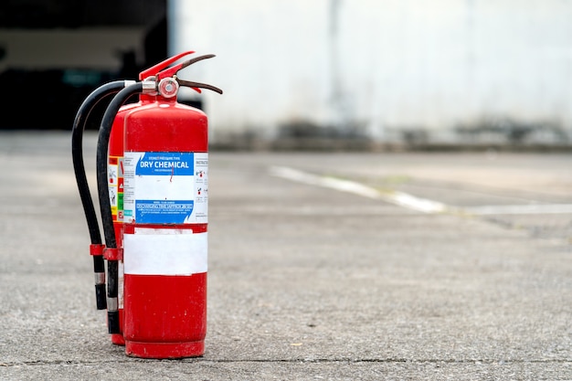 Estintore rosso del primo piano con il fuoco molle e sopra luce nei precedenti