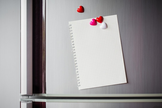 Estratto della clip del cuore di legno con la carta in bianco e la carta del bastone sullo spazio della copia della nota della carta della porta del frigorifero per aggiungere il fondo del messaggio dell'immagine del biglietto di S. Valentino del testo