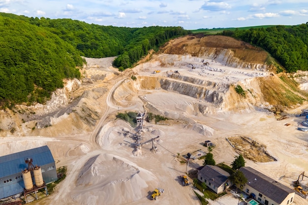 Estrazione a cielo aperto di materiali da costruzione in pietra arenaria con escavatori e dumper.