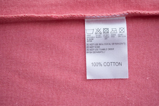 Etichetta bianca per i vestiti con istruzioni di lavaggio per la cura del bucato sulla maglietta di cotone