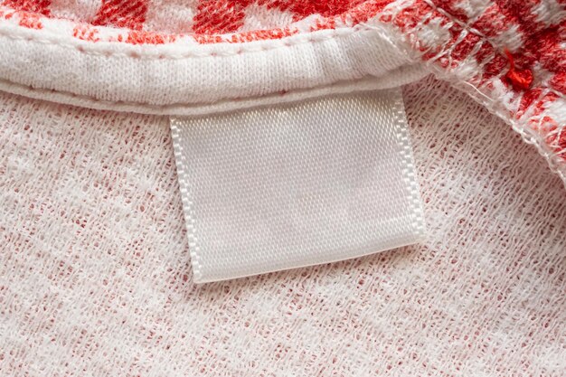 Etichetta di vestiti per la cura della lavanderia in bianco bianco su sfondo di camicia di cotone