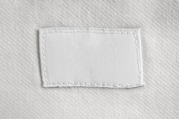 Etichetta di vestiti per la cura della lavanderia in bianco bianco su sfondo di camicia di cotone