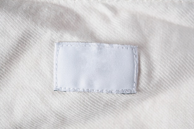 Etichetta di vestiti per la cura della lavanderia in bianco bianco sulla camicia di cotone