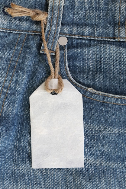 Etichetta in carta bianca con corda di canapa legata su jeans o jeans.