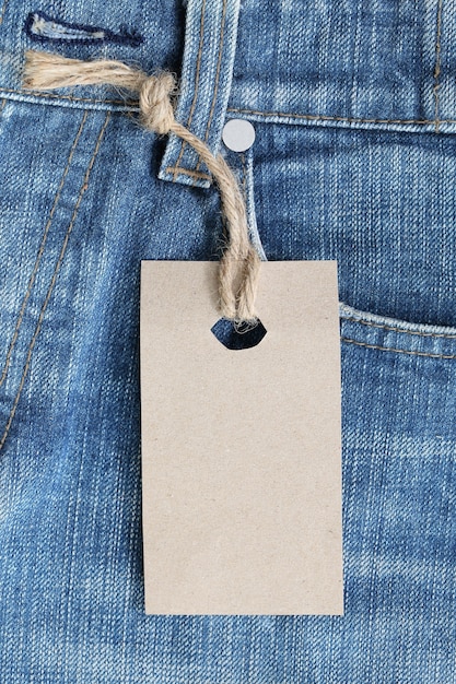 Etichetta in carta marrone con corda di canapa legata su jeans o jeans.