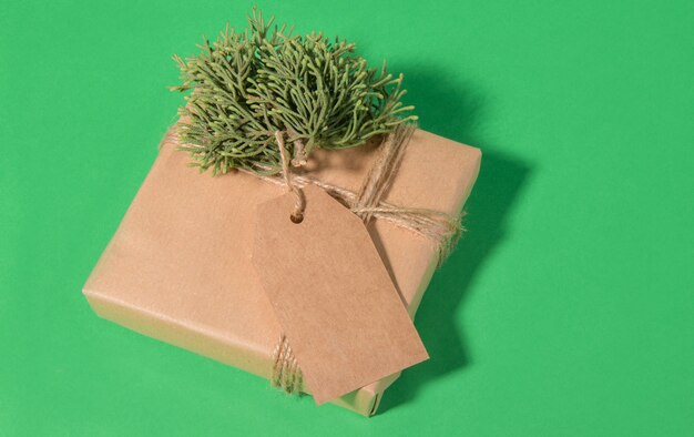 Etichetta regalo di Natale mock up con regalo avvolto in carta riciclata kaft su verde