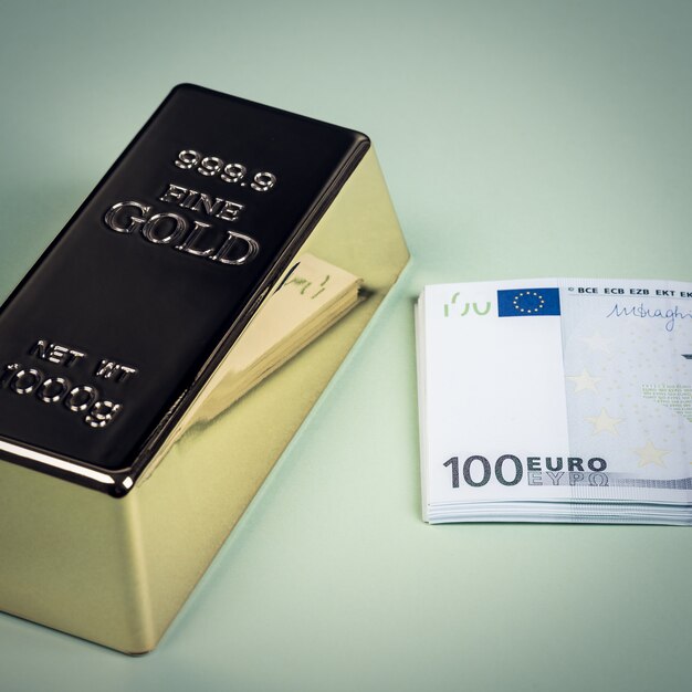 Euro contanti e lingotto d'oro su uno sfondo verde