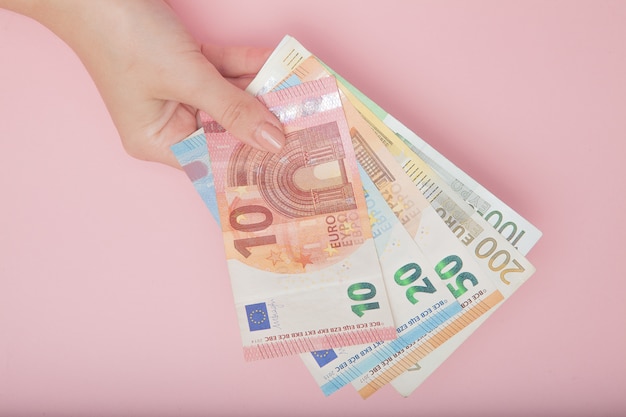 Euro soldi delle banconote in mani femminili su fondo rosa. Concetto di business e Instagram