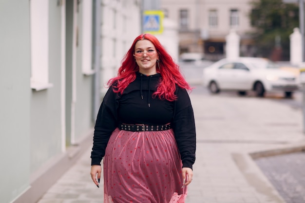 Europea plus size donna giovane rosso rosa dai capelli corpo positivo ragazza a piedi in strada della città all'aperto