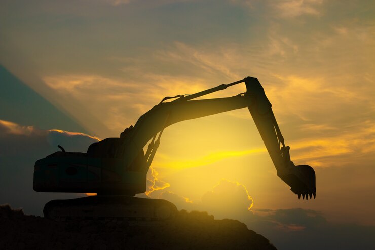 Excavators are working hard on sunset sky.