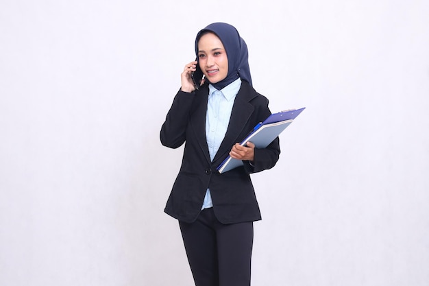 Exclusive indonesia donna d'ufficio che indossa un hijab si trova sorridendo e chiama la gente e porta una penna c