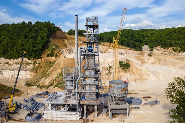 Fabbrica di cemento all'estrazione a cielo aperto di materiali in pietra arenaria da costruzione con escavatori e autocarri con cassone ribaltabile.