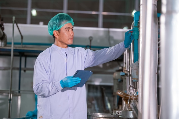 Fabbrica di ingegneri asiatici Tecnologo professionista che utilizza tablet in un impianto di produzione per controllare produttività e qualità