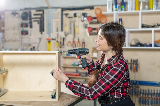 fabbrica di mobili, piccole imprese e concetto di lavoratrice - donna con un trapano sul