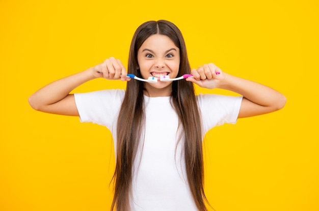 Faccia buffa Ragazza adolescente che si lava i denti su sfondo giallo isolato Igiene quotidiana bambino adolescente tenere spazzolino routine mattutina Salute dentale cura orale