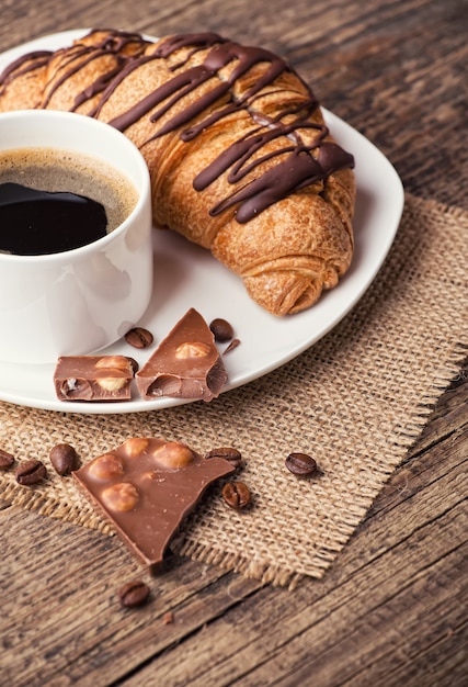 Faccia colazione con caffè, cioccolato e i croissant sulla tavola di legno