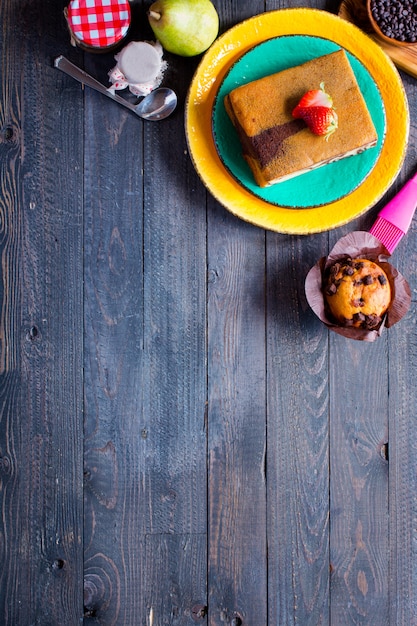 Faccia colazione con differenti pasticcini e frutti su una tavola di legno