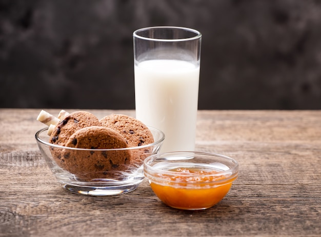 Faccia colazione con latte e i biscotti sulla tavola di legno