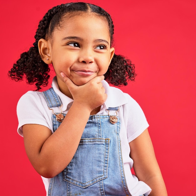 Faccia da bambina o mano pensante sul mento su sfondo rosso isolato in giochi innovazione studio domanda o visione divertente Sorridi bambino felice o curioso con idee vestiti di moda o stile di capelli ricci