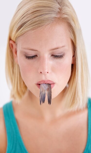 Faccia di donna e coda di pesce con sorpresa su sfondo bianco studio o mockup dieta pazza e persona con dubbio in cucina di frutti di mare strani e sapore di tonno grossolano o cibo strano in bocca