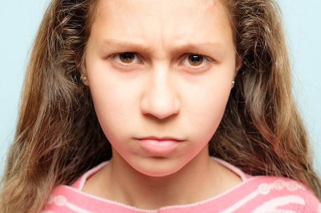 Faccia di emozione. bambino accigliato e scontroso con labbra increspate e sguardo penetrante. ritratto di ragazza.