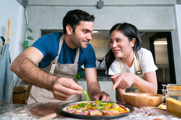 Faccia di pasta per pizza italiana fatta in casa con verdure e salsa cucinata da coppia amore chef a casa sul tavolo nella cucina moderna felice momento di famiglia insieme