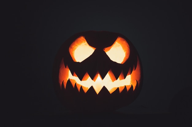 Faccia di zucca di Halloween con candela accesa su sfondo nero Faccia spettrale