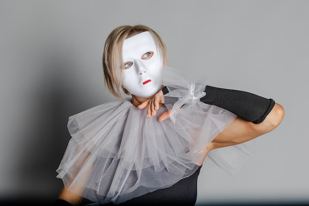 Faccia dietro maschera Donna con maschera teatrale bianca e collare arlecchino su sfondo grigio Abiti da mascherata di fantasia