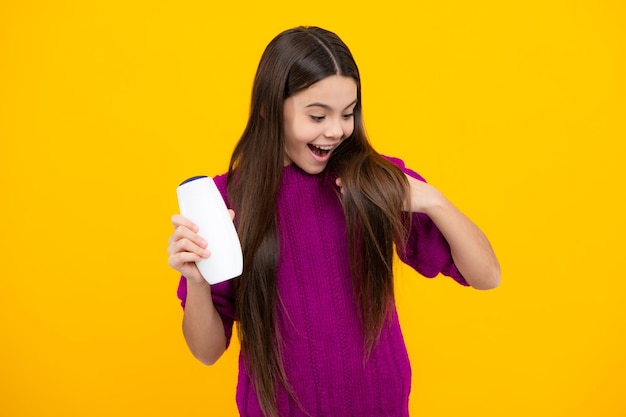 Faccia eccitata Adolescente bambina che mostra bottiglia balsami shampoo o gel doccia Prodotto cosmetico per capelli Bottiglia per pubblicità mock up copy space Espressione stupita allegra e felice