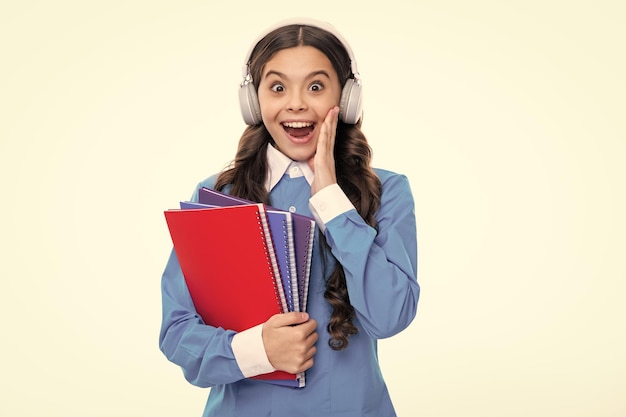 Faccia eccitata Scuola bambino ragazza con le cuffie e libro isoalted su sfondo bianco Stupito