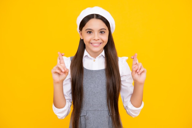 Faccia felice emozioni positive e sorridenti della ragazza adolescente Felice bambino adolescente allegro che desidera buona fortuna incrocia le dita ha fede per meglio isolato su sfondo giallo