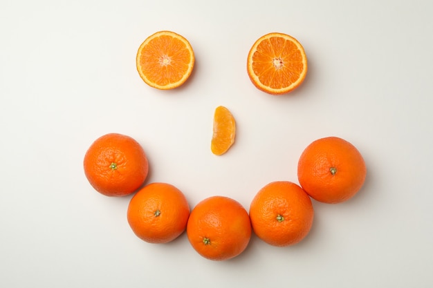 Faccia felice fatta di mandarini su bianco