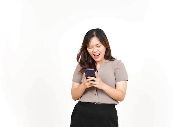 Faccia scioccata che tiene e usa lo smartphone della bella donna asiatica isolata su sfondo bianco